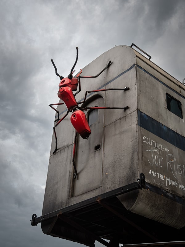 An art sculpture of a giant ant crawling over a subway carriage